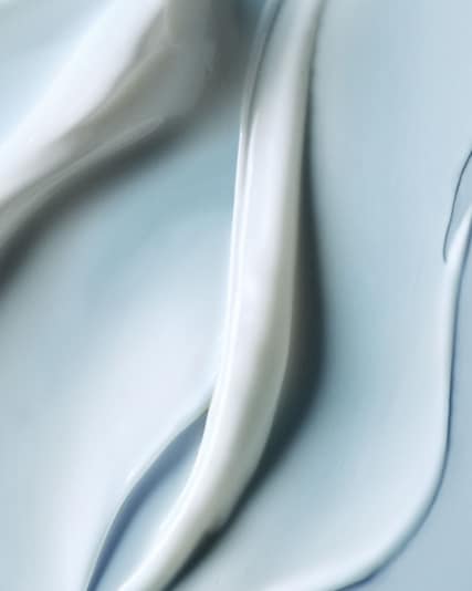 Macro photograph of the moisturising soft cream texture in smooth waves on flat surface.